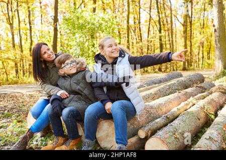 Mère et deux enfants s'assoient en rondins et s'amusent lors d'un voyage dans la nature en forêt Banque D'Images