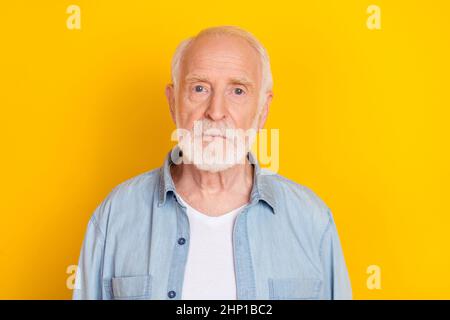 Portrait d'un homme aux cheveux gris sérieux et attrayant portant une chemise confortable isolée sur un fond jaune vif Banque D'Images