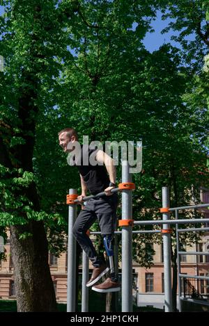 jeune homme athlétique avec jambe artificielle qui s'efforce sur un barres Banque D'Images