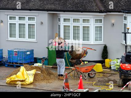 Un constructeur utilisant un mélangeur de ciment à l'extérieur d'une maison privée en cours de construction, Shepperton Surrey Angleterre Royaume-Uni Banque D'Images