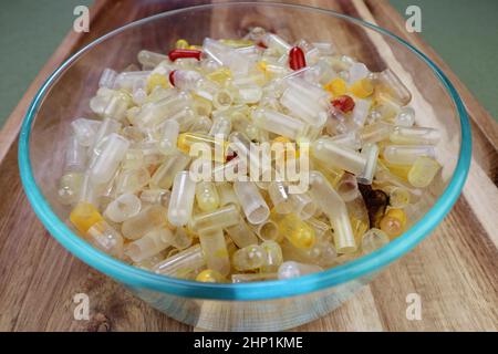 Capsules et contenants de supplément de santé accumulés dans un bol en verre transparent près d'une table. Vidé avec les capsules de supplément de santé de résidus fermer Banque D'Images