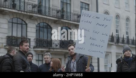 Londres, Royaume-Uni - 01 22 2022: L'homme protestant à Portland place tenant un panneau, «Comment pouvez-vous vous détourner pendant qu'ils mentent et nous tuer pour l'argent et le contrôle». Banque D'Images