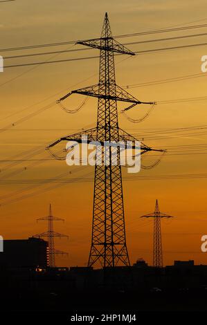 Silhouettes de pylônes haute tension à Francfort dans la lueur du soir. Banque D'Images