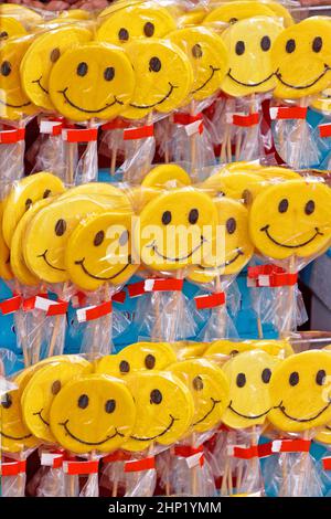 Cercle jaune smiley faces lollipops vendus sur le marché de la foire de pays Banque D'Images