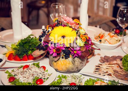 Décoration de mariage d'automne de style rustique avec fleurs et citrouilles sur les tables des invités dans le restaurant lors d'un banquet festif. Arrangeurs de fleurs de table Banque D'Images