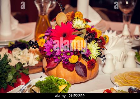 Décoration de mariage d'automne de style rustique avec fleurs et citrouilles sur les tables des invités dans le restaurant lors d'un banquet festif. Arrangeurs de fleurs de table Banque D'Images