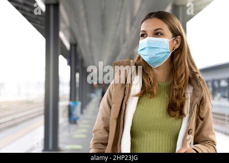 Femme de banlieue portant un masque chirurgical en train d'attente à la gare à l'extérieur.Copier l'espace. Banque D'Images