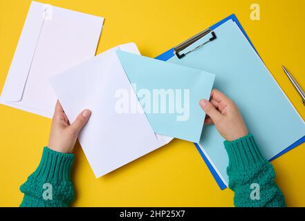 main femelle pour les enveloppes en papier blanc sur fond orange, vue de dessus.Envoi et réception de correspondance Banque D'Images