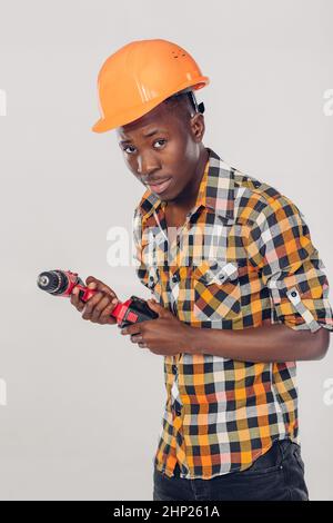 African American construction worker in casque utilise tournevis électrique Banque D'Images