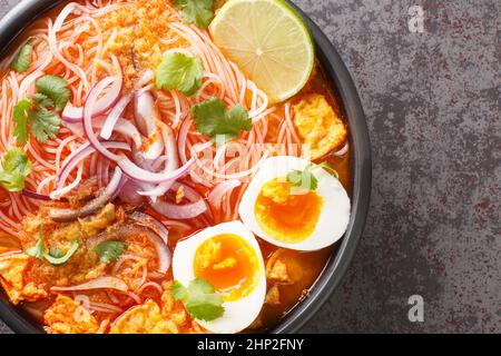 Mohinga est une soupe de nouilles de riz et de poisson du Myanmar et une partie essentielle de la cuisine birmane à proximité dans le bol sur la table. Vue horizontale du dessus avant Banque D'Images