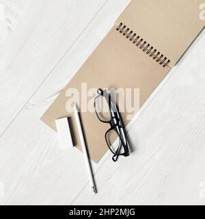 Carnet kraft vierge, lunettes, crayon et gomme sur fond en bois clair.Modèle pour placer votre conception.Vue de dessus.Pose à plat. Banque D'Images