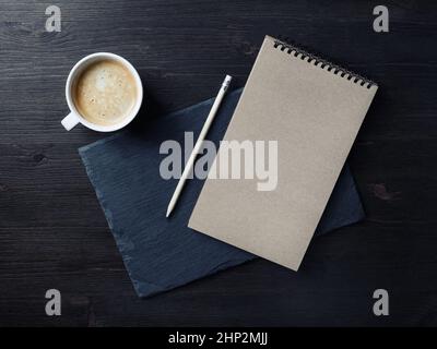 Photo du bloc-notes kraft vierge, du crayon et de la tasse à café.Maquette de marque.Vue de dessus.Pose à plat. Banque D'Images