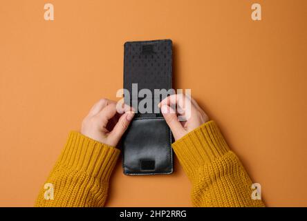deux mains de femme tiennent le cuir noir ouvert vide portefeuille pour l'argent, vue du dessus Banque D'Images