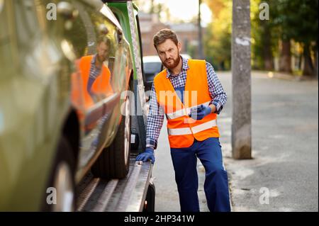 Un travailleur de remorquage concentré dans le contrôle uniforme de la précision du chargement de la voiture.Préparation à l'évacuation Banque D'Images