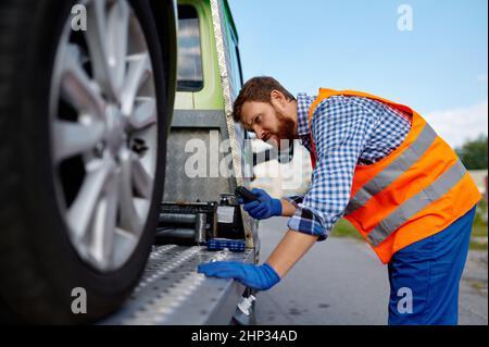 Opérateur de chariot de remorquage fixant la voiture sur la plate-forme.Homme travaillant avec un véhicule en panne Banque D'Images