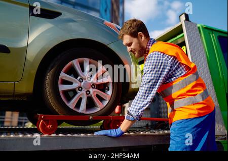 Opérateur de chariot de remorquage fixant la voiture sur la plate-forme.Homme travaillant avec un véhicule en panne Banque D'Images