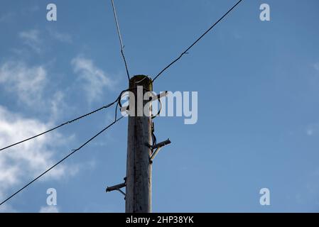 Point de vue à angle bas d'un poteau téléphonique transportant des lignes téléphoniques domestiques au Royaume-Uni Banque D'Images