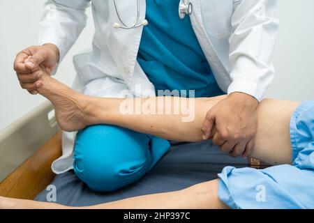 Médecin asiatique physiothérapeute examinant, massant et traitement genou et jambe d'un patient senior dans la clinique orthopédique infirmière hôpital. Banque D'Images