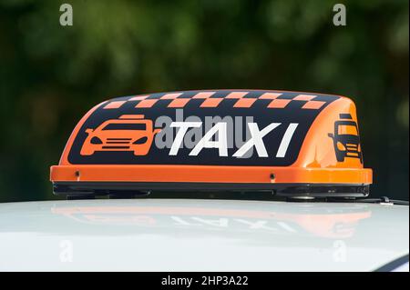 un panneau de taxi orange se trouve sur le toit de la voiture. Photo de haute qualité Banque D'Images