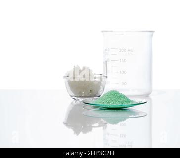 Sulfate ferreux dans le verre de surveillance chimique, placer à côté du sel en flocons et du bécher.Gros plan sur l'ingrédient chimique sur la table de laboratoire blanche.Vue latérale Banque D'Images