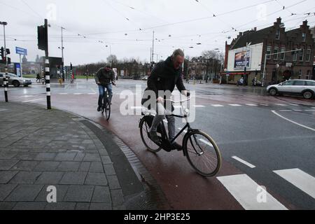 Amsterdam, pays-Bas. 18th févr. 2022. Les cyclistes se battent contre les vents violents dans la rue le 18 février 2022 à Amsterdam, aux pays-Bas. Le bureau météorologique néerlandais de KNMI a émis un code rouge d'avertissement météorologique pour la côte et l'orange pour le reste du pays, les transports publics, les services de trains internationaux et plus de 165 vols à partir de l'aéroport de Schiphol ont été annulés à partir de 2pm. (Photo de Paulo Amorim/Sipa USA) Credit: SIPA USA/Alay Live News Banque D'Images