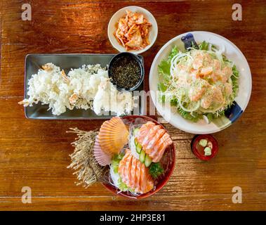 Vue de dessus de l'ensemble de la cuisine japonaise comme sushis frais, salade de saumon, tempura de crevettes sur table en bois, concentration sélective Banque D'Images