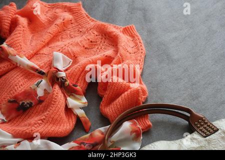 Pose à plat des vêtements et accessoires de printemps pour femmes. Chandail rose, robe, sac à main sur fond gris . Banque D'Images