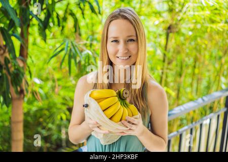 Banane dans un sac réutilisable dans les mains d'une jeune femme. Concept zéro déchet, concept sans plastique. Saine alimentation propre et détox. Fruits d'été Banque D'Images