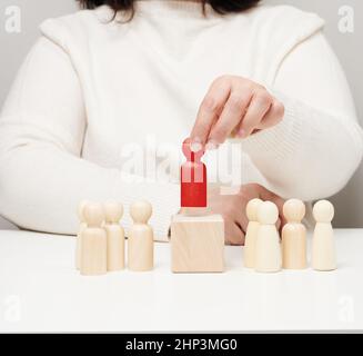 la femme garde la figurine en bois rouge séparée du groupe.Concept de développement de carrière, personne unique.Trouver un employé talentueux Banque D'Images