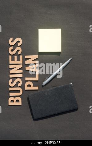 Main d'homme d'affaires plaçant un stylo et un carnet devant le plan d'affaires Word fait de blocs de bois de lettres Alphabet.Vue grand angle.Rétrogr. Vertical Banque D'Images