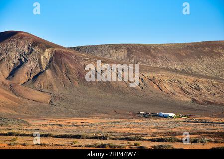 Magnifique paysage volcanique avec une maison blanche en face.Près de Costa Teguise, Lanzarote, Iles Canaries, Espagne.Image prise sur le terrain public. Banque D'Images