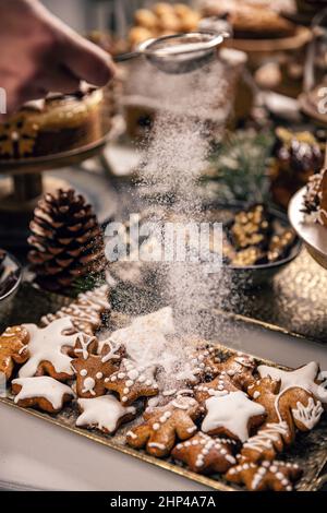 Saupoudrer le sucre glace à la main sur les biscuits au pain d'épice.Concept de cookie de Noël Banque D'Images