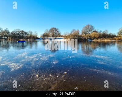 Vue sur le lac gelé avec reflet du ciel bleu par temps clair Banque D'Images