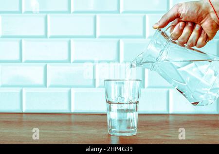 La main d'un homme verse de l'eau pure fraîche de la bouteille dans un verre sur la table, concept de santé et de régime, ralenti vidéo Banque D'Images