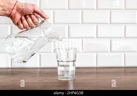 La main d'un homme verse de l'eau pure fraîche de la bouteille dans un verre sur la table, concept de santé et de régime, ralenti vidéo Banque D'Images