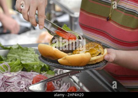 Hamburgers et hot-dogs cuisant sur le Bar-B-Q au Club Cookout pour les enfants et les familles Banque D'Images