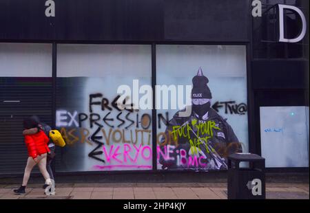 Manchester, Royaume-Uni, 18th février 2022. Une fresque humoristique présentant le Premier ministre britannique Boris Johnson sur l'ancien magasin Debenhams dans le centre de Manchester, au Royaume-Uni, a été vandalisée deux fois jusqu'à présent avec des graffitis. Réalisée par 'Foka Wolf', une artiste de rue, la fresque a la tête de Boris Johnson, portant un chapeau de fête, sur l'image d'un policier armé. Il y a une enquête policière sur les parties au 10 Downing Street pendant les écluses de Covid-19. L'artiste a mentionné ce qu'il considère comme des « deux normes » du gouvernement. Les gens marchent au-delà de la fresque. Crédit : Terry Waller/Alay Live News Banque D'Images