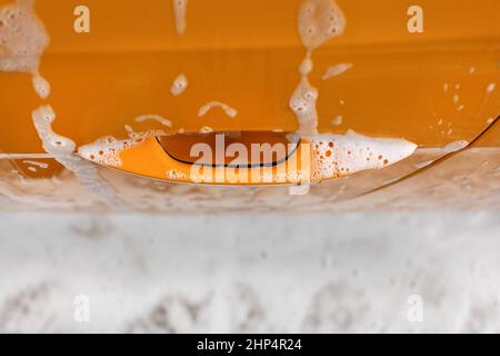 Poignée de porte de voiture jaune couverts avec du shampoing et de mousse au lavage en lave-auto. Banque D'Images