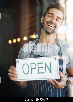 Nous allons vous préparer un café. Photo d'un beau jeune homme qui pendait une affiche ouverte sur la porte de son magasin. Banque D'Images