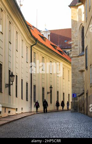 Ombre matinale dans une étroite rue pavée du château de Prague avec des bâtiments classiques et une lanterne traditionnelle de la rue, avec des touristes, Prague Banque D'Images