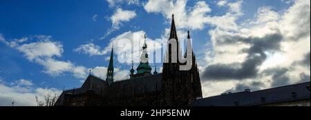 Les flèches et la coupole de la cathédrale Saint-Vitus en silhouette face d'un ciel bleu avec des nuages blancs au château de Prague, Prague, République tchèque Banque D'Images