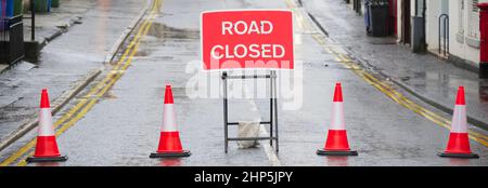 Panneau fermé route devant avec cônes de circulation et passage de barrière rouge Banque D'Images