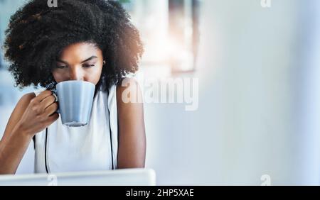 Le café l'amène à aller. Photo rognée d'une jeune femme d'affaires attirante buvant une tasse de café dans son bureau. Banque D'Images