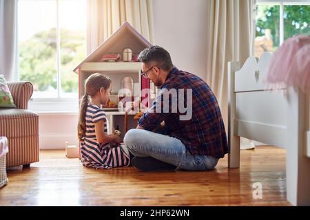 Donner à ses poupées un endroit pour appeler à la maison. Photo d'une petite fille jouant avec une maison de poupées à la maison. Banque D'Images