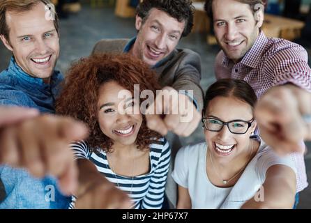 Nous devons notre succès à vous. Portrait d'un groupe de collègues souriants pointant vers l'appareil photo lorsqu'ils sont debout dans un bureau. Banque D'Images