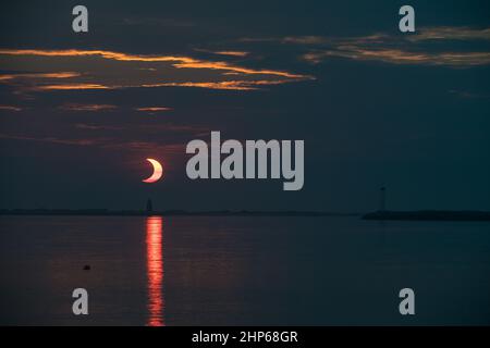 Une éclipse solaire partielle est vue lorsque le soleil se lève derrière le phare de Delaware Breakwater, le jeudi 10 juin 2021, à Lewes Beach, dans le Delaware. L'éclipse solaire annulaire ou « anneau de feu » n'est visible que dans certaines parties du Groenland, du nord de la Russie et du Canada. Banque D'Images