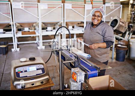 Pesé pour le profit. Photo d'un employé de l'usine utilisant une échelle industrielle à l'intérieur de l'entrepôt. Banque D'Images