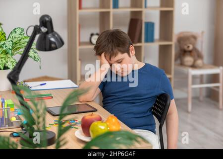 L'étudiant s'endormira à la maison à son bureau tout en résolvant les devoirs à l'école. Banque D'Images