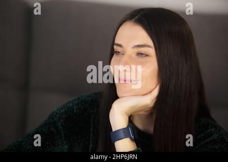 Bonne femme blanche pensant à l'avenir avec un sourire joyeux. Belle femme brunette portant des montres-bracelets intelligentes modernes et regardant loin. Portrait o Banque D'Images