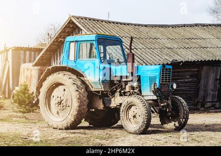 Un vieux tracteur dans la campagne au milieu des granges et des hangars Banque D'Images